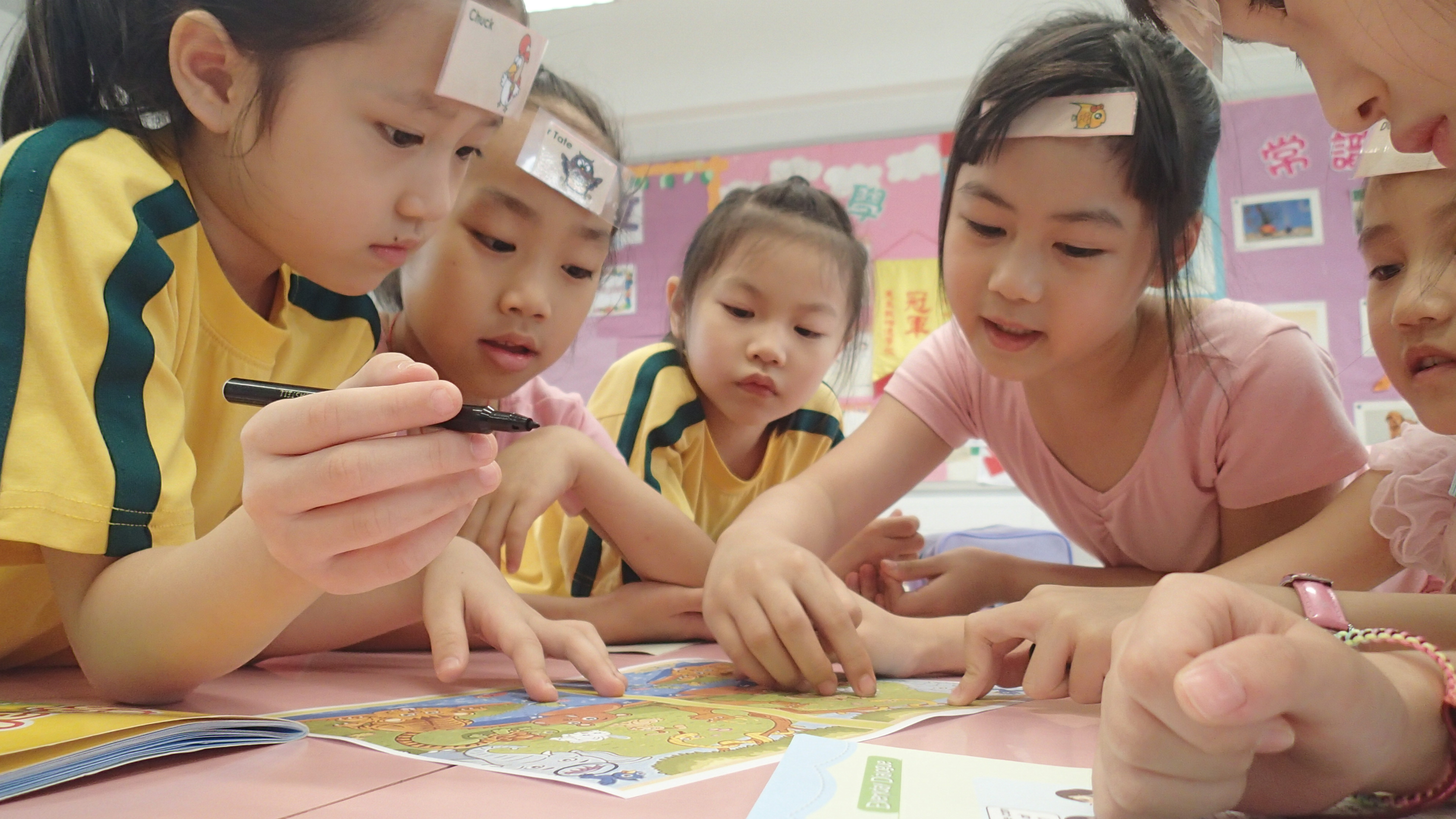 a group of asian girls are playing a table game in a TEFL classroom